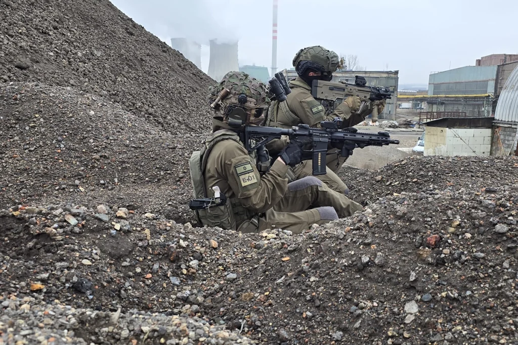 Special forces soldiers in full tactical equipment, armed with rifles featuring optics and accessories, conducting an urban operation.