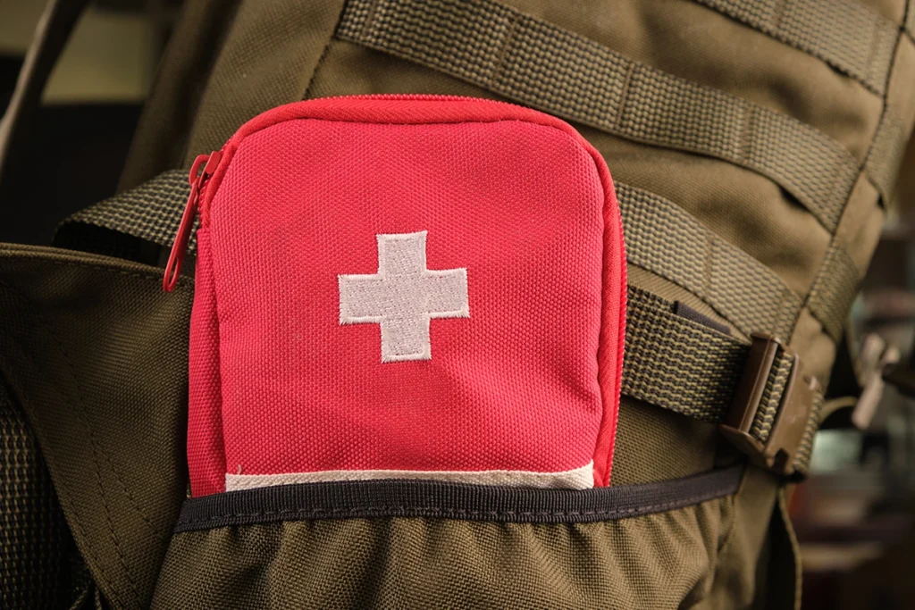red tactical first aid kit attached to a backpack with molle system