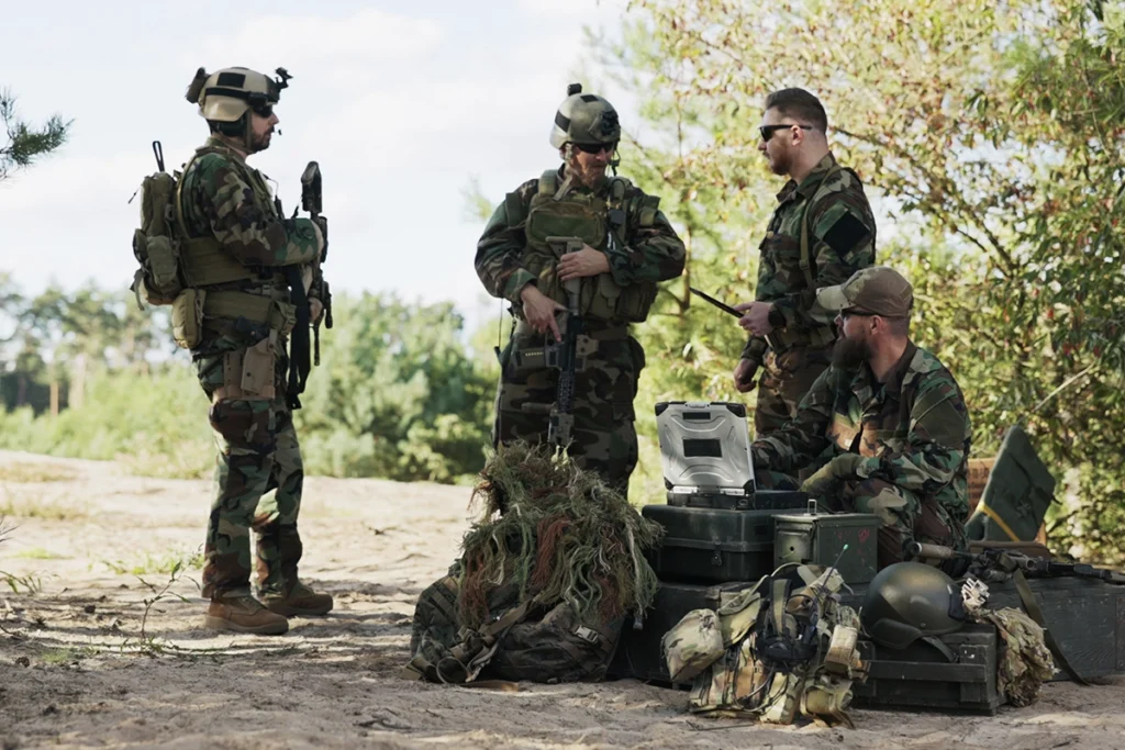 soldiers in the field equipped with professional tactical gear including helmets, backpacks, and combat loadout