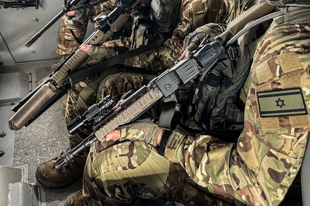 Taktyczna latarka na broń długą zamontowana na karabinie operatora w pojeździe wojskowym.